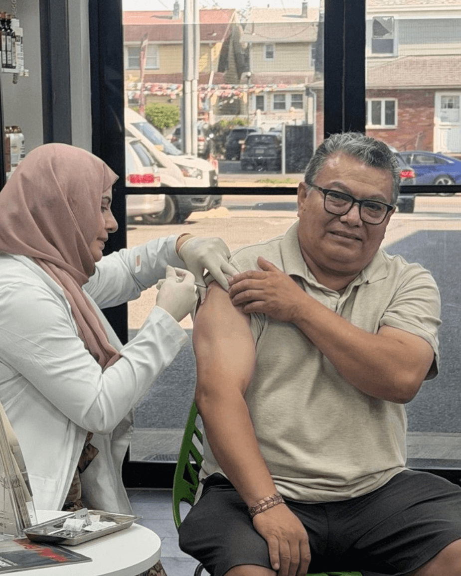 A licensed CureMed pharmacist administering a weight loss injection to a seated patient inside the pharmacy